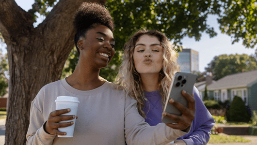 Two friends taking selfies outdoors.