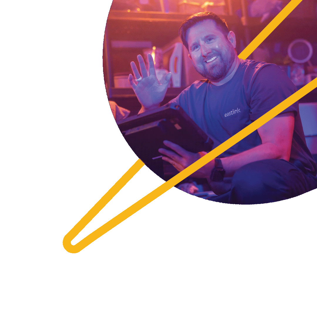 An Eastlink technician smiling and waving while he sets up a customer's internet.